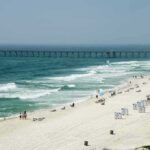 Sandy beach with turquoise waves and a long pier