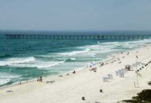 Sandy beach with turquoise waves and a long pier