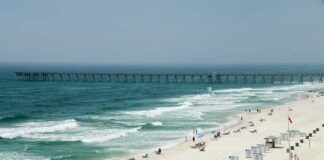 Sandy beach with turquoise waves and a long pier