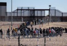 Africans Who Stormed Spanish Border Are Pooping Everywhere Crowd of people lining up near a border fence with barbed wire