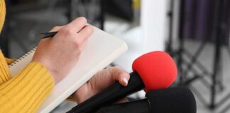 LSU Upends Football – Ignites War With SEC Journalist holding two microphones while writing in a notebook