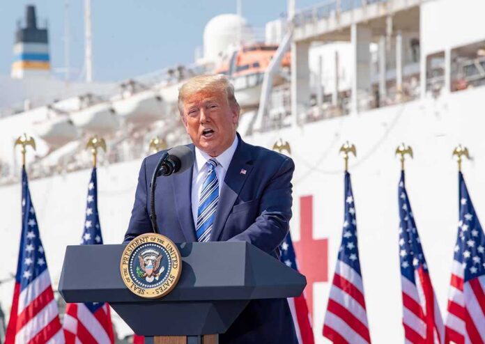 President,Donald,J.,Trump,Delivers,Remarks,During,His,Visit,To Donald Trump speaking at a podium with American flags and a ship in the background
