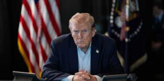 Republican Candidates Are Running From Trump Donald Trump seated at a table between two desk phones