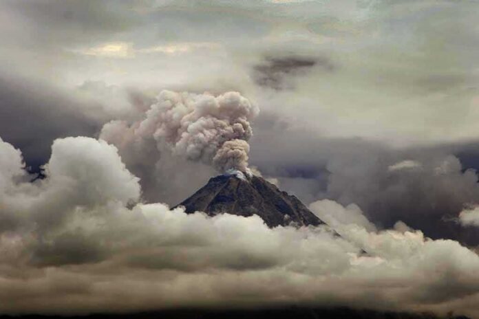 shutterstock_1190133376 Volcano erupting with ash plume above cloud layer