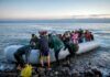 People arriving in a crowded inflatable boat at a rocky shore