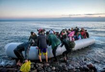 People arriving in a crowded inflatable boat at a rocky shore