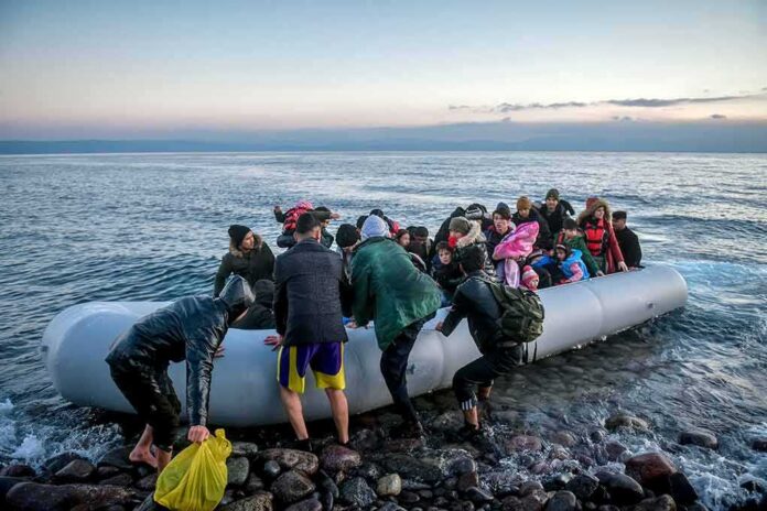 shutterstock_1661385784 People arriving in a crowded inflatable boat at a rocky shore