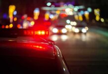 5 Men DEAD – Police Investigating Serial Killer Police car with flashing red lights on a city street at night