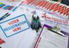 DOJ Gives State 48 Hours to Check Noncitizen Names on Voter Rolls OR ELSE Voter registration table with forms, pens, and informational materials