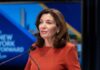 Kathy Hochul speaking at a podium with microphones
