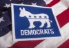 Dem Candidate BUTCHERS THE BIBLE – Ignites Senate Race Brawl Democrats donkey symbol on a blue sign over an American flag