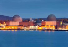 Neglected Red-State Builds America’s Biggest Nuclear Plant nuclear power plant with two domed reactor buildings by water at dusk