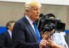 Donald Trump speaking with media cameras in the background