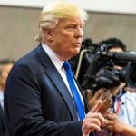 Donald Trump speaking with media cameras in the background