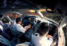 Bleeding Pilot Reveals How He Outsmarted Hijacker Mid-Flight Pilots in an airplane cockpit during city approach at sunset