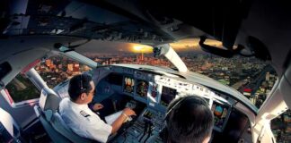 Bleeding Pilot Reveals How He Outsmarted Hijacker Mid-Flight Pilots in an airplane cockpit during city approach at sunset