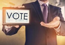 Fake Polls Fooled Big Media! Businessperson holding a tablet displaying the word VOTE