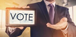 Fake Polls Fooled Big Media! Businessperson holding a tablet displaying the word VOTE