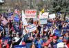 Trump’s Onstage Pardon Sparks DOJ U-Turn Questions Tim Teufel, Christian Jones, and Nash the Slash among a crowd at a political rally holding signs and flags